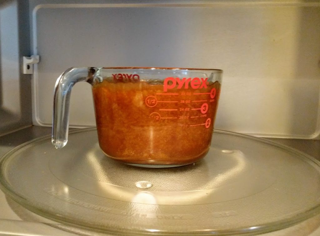 pyrex dish sitting in a microwave with brown mixtrue in it