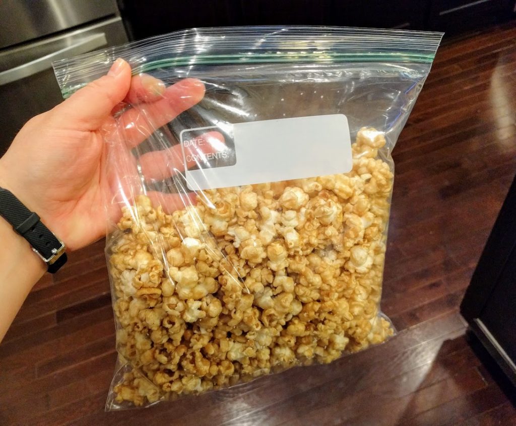 hand holing a zip top bag of salted caramel popcorn