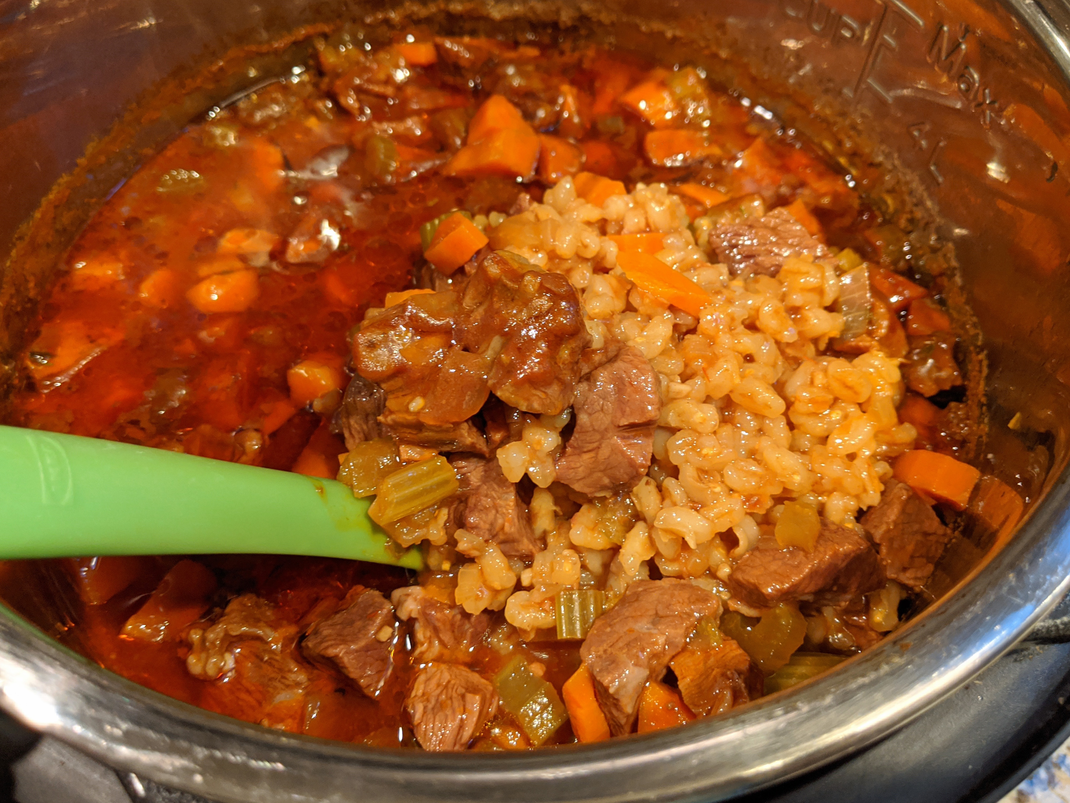 green ladle in pot of beef barley soup