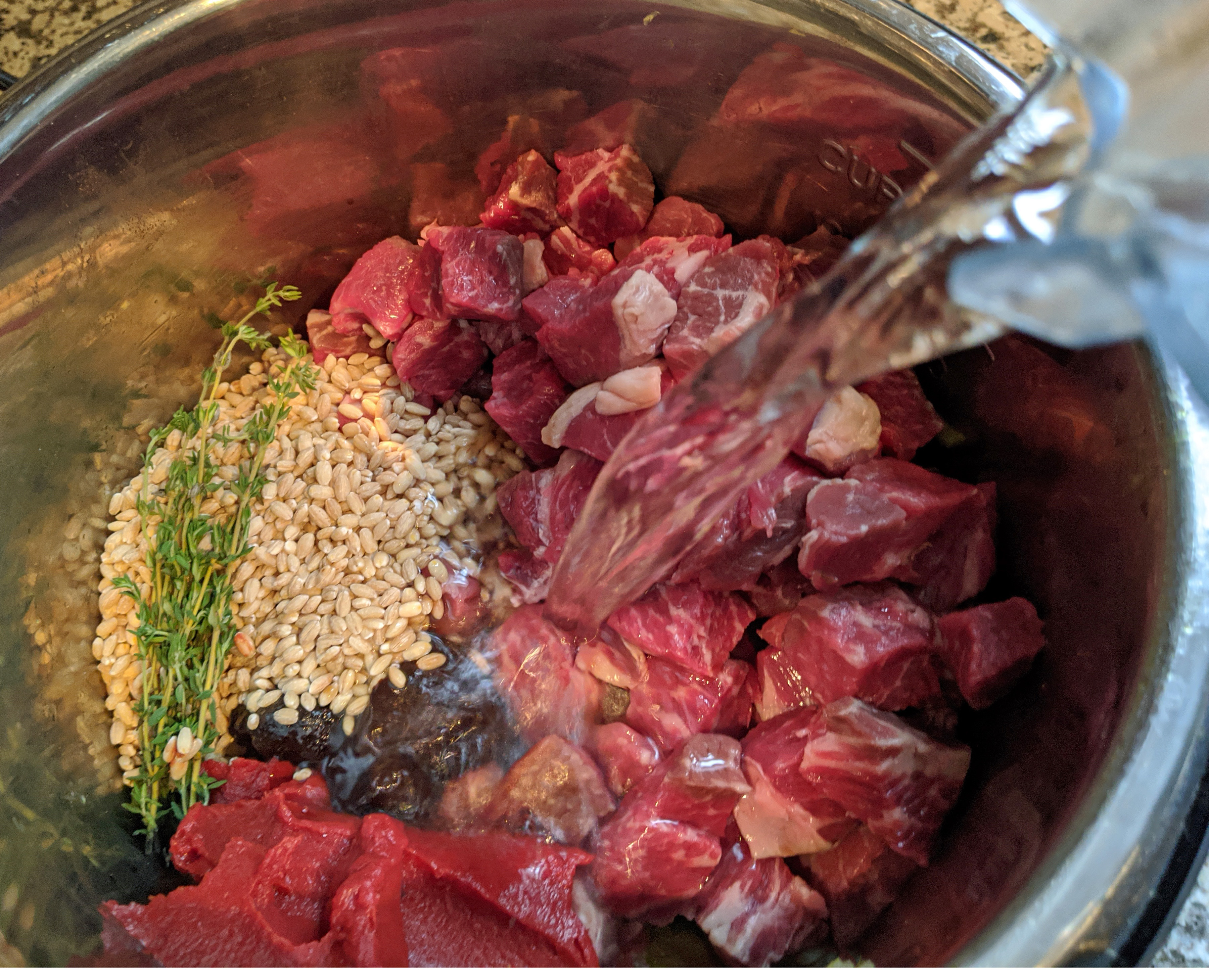 water pouring over pearl barley, thyme and beef chuck roast