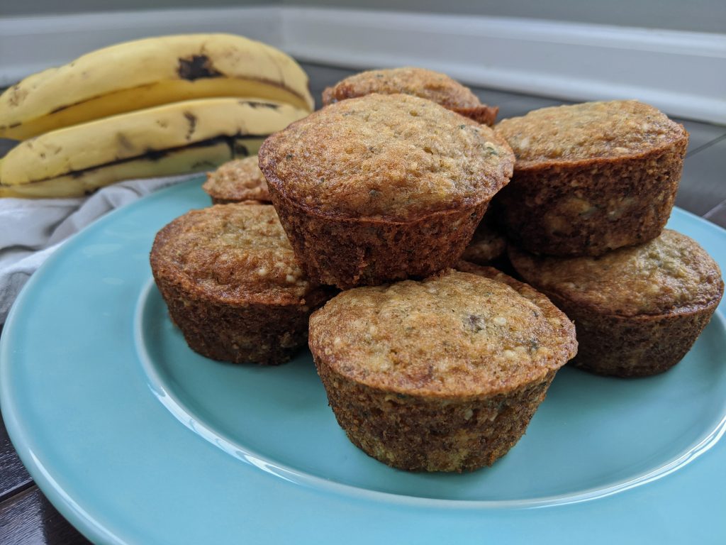 blue plate with 7 muffins on it and bananas in the background 