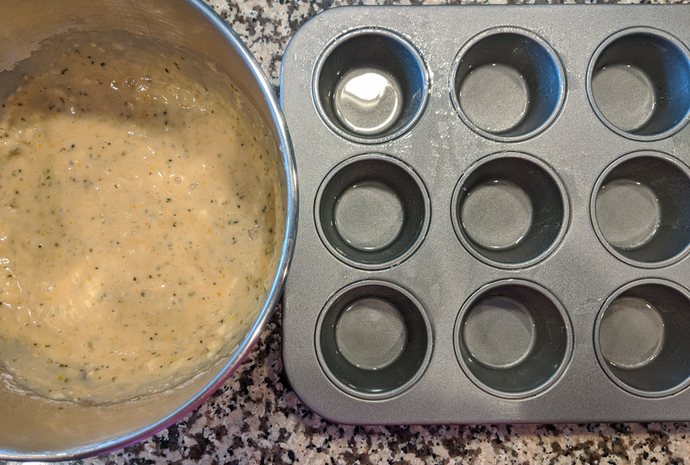 bowl of batter next to an empty muffin tin