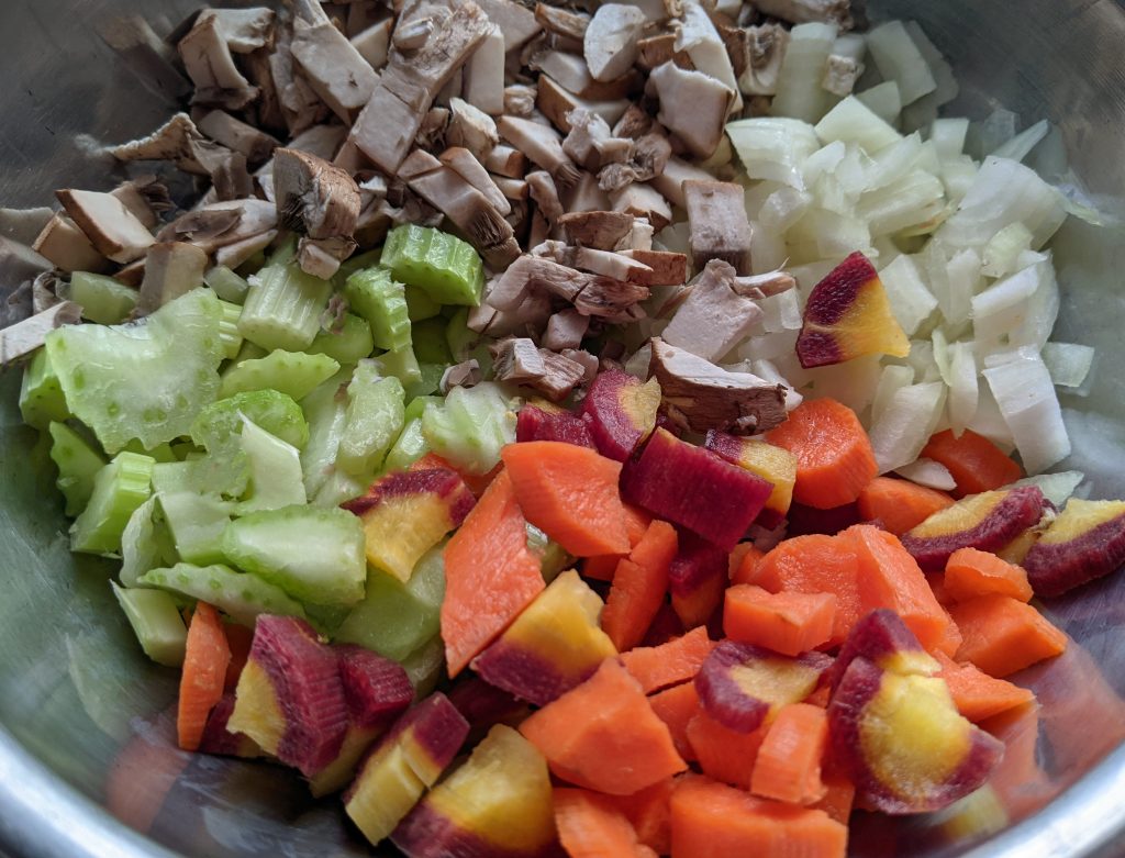 close up picture of chopped carrots, onions, mushrooms, and celery