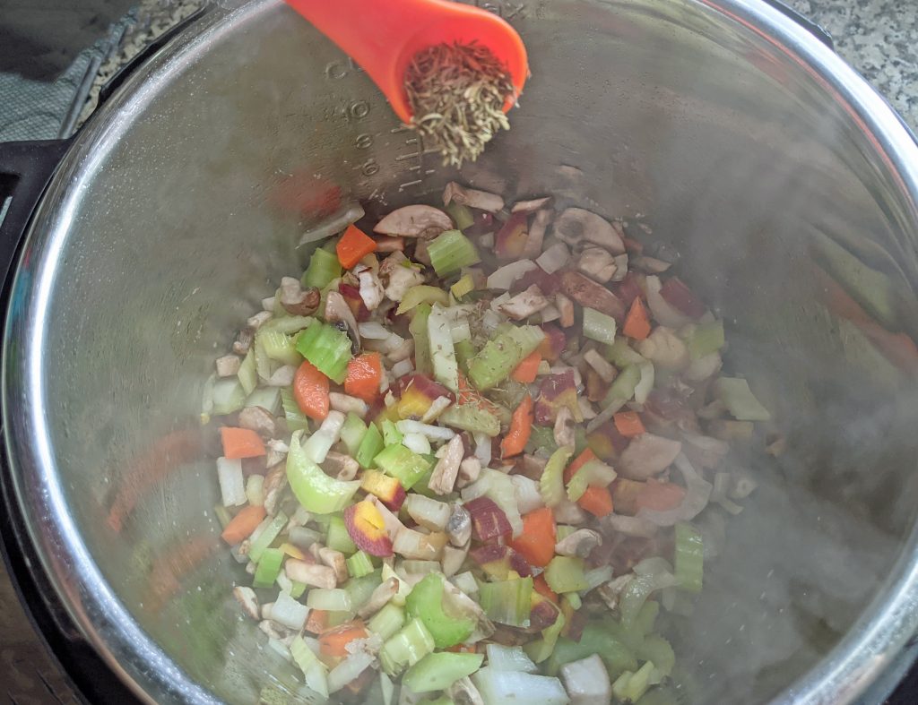 teaspoon of dried thyme being poured into the instant pot